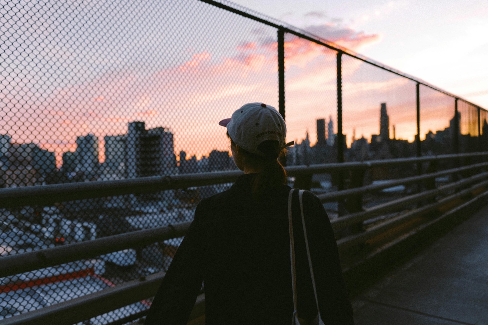 A person on a bridge at sunset looking out over the New York City skyline